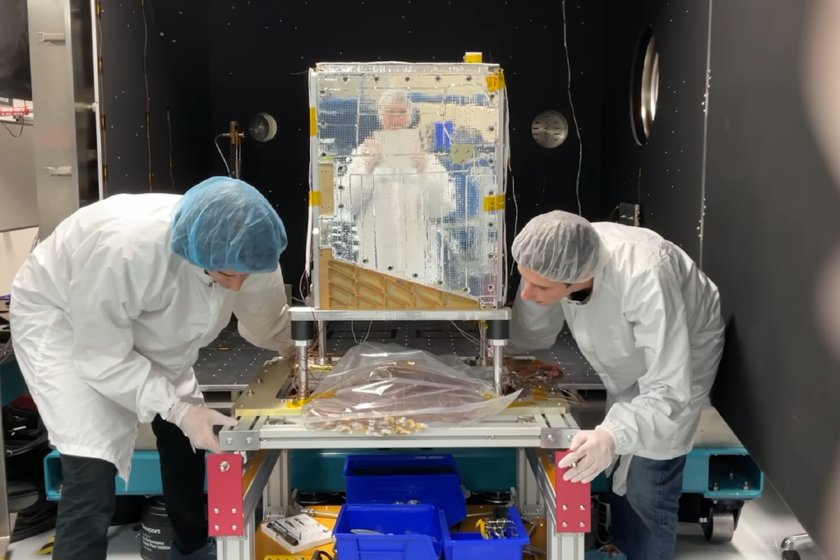 Dos ingenieros con ropa de sala limpia trabajan sobre un prototipo de satélite del Proyecto Suncatcher de Google
