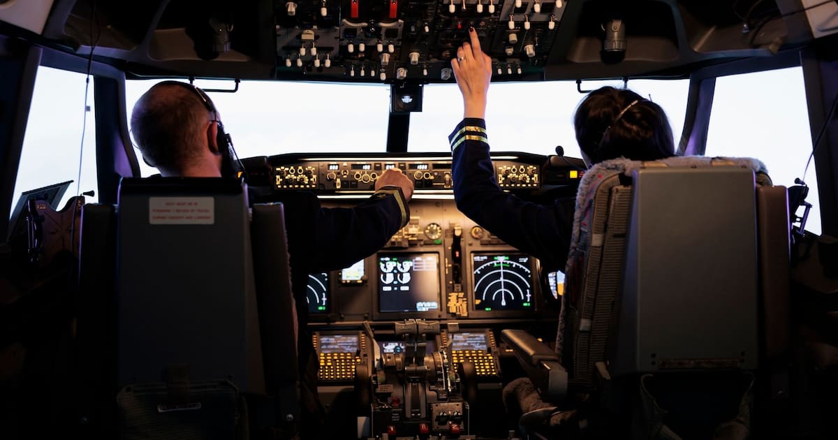 Dos pilotos operan los comandos en la cabina de un avión