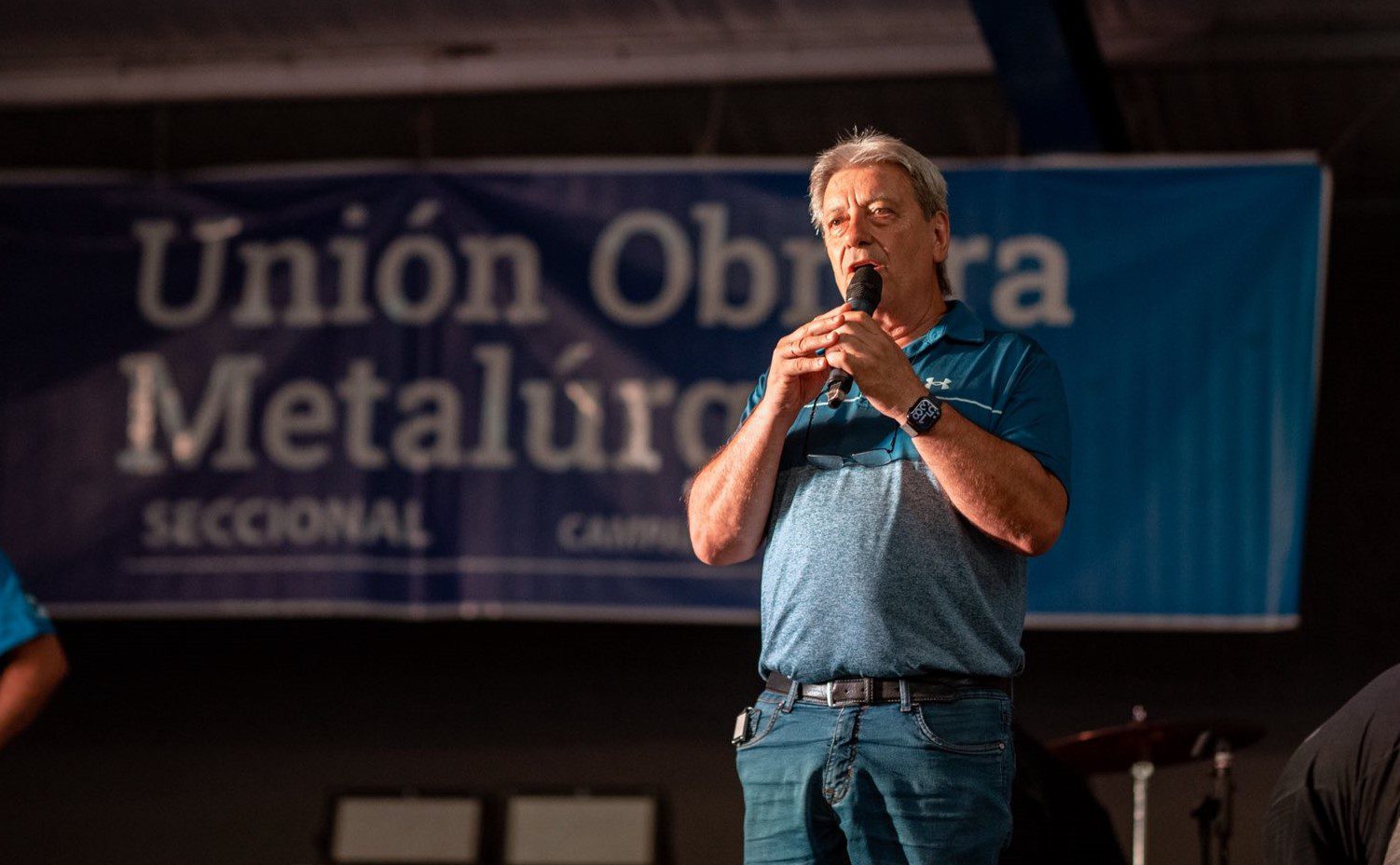 Abel Furlan hablando frente a una bandera de la Union Obrera Metalurgica