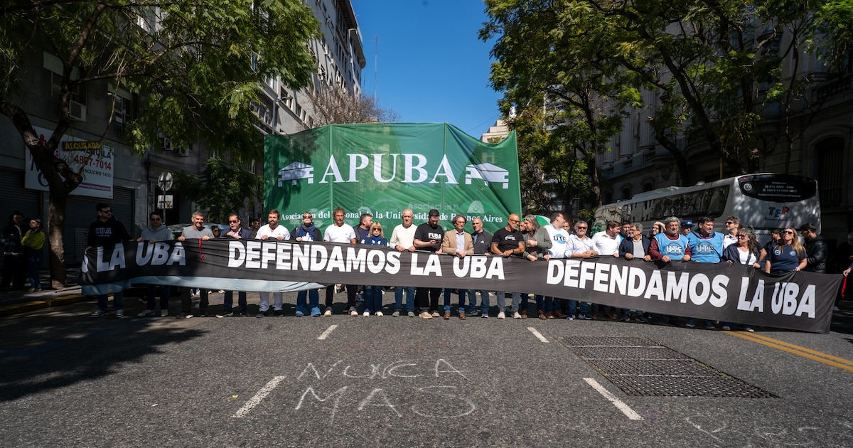 Docentes y no docentes de la UBA con una bandera que dice Defendamos la UBA
