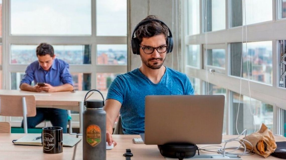 Persona trabajando con notebook y auriculares en una oficina