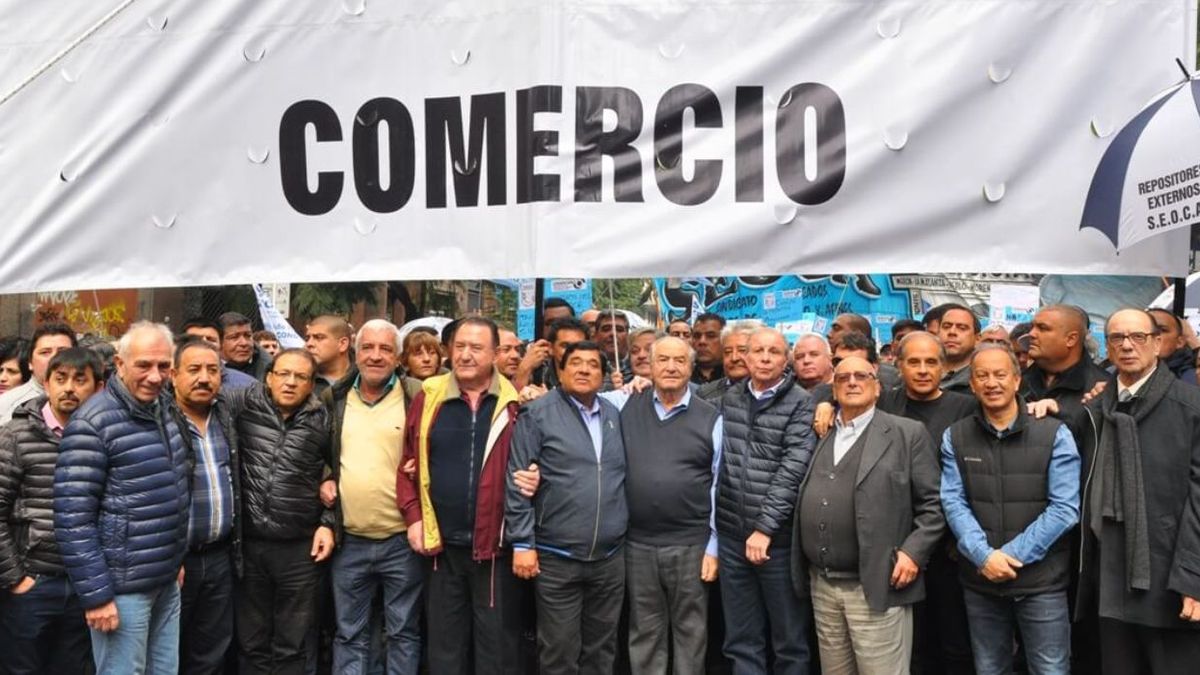 Dirigentes de la FAECyS detrás de una bandera que dice Comercio durante una movilización gremial